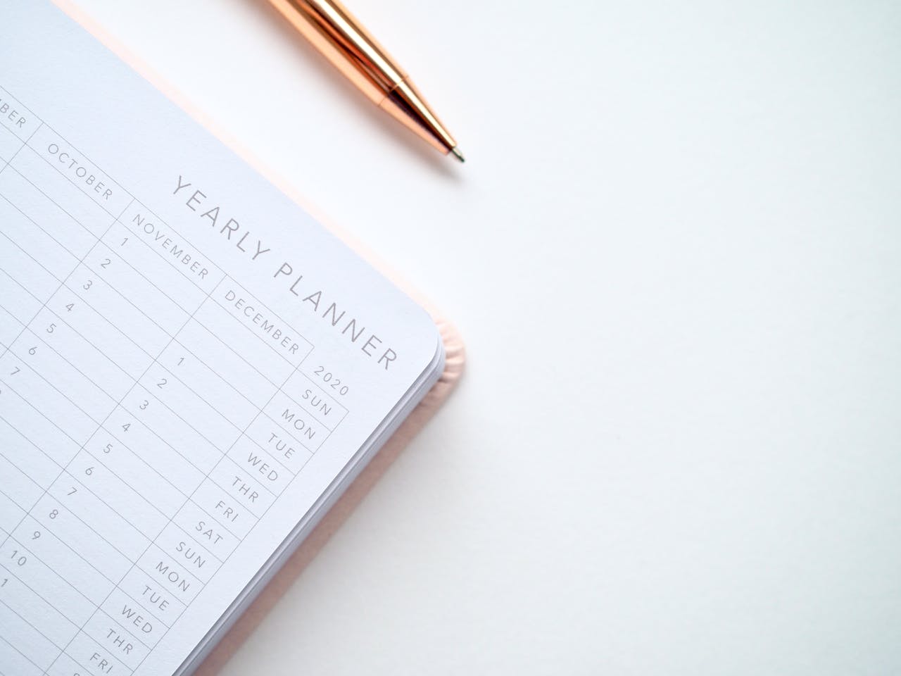 Caneta e planner anual sobre um fundo branco, representando o método 1 ano em 12 semanas.