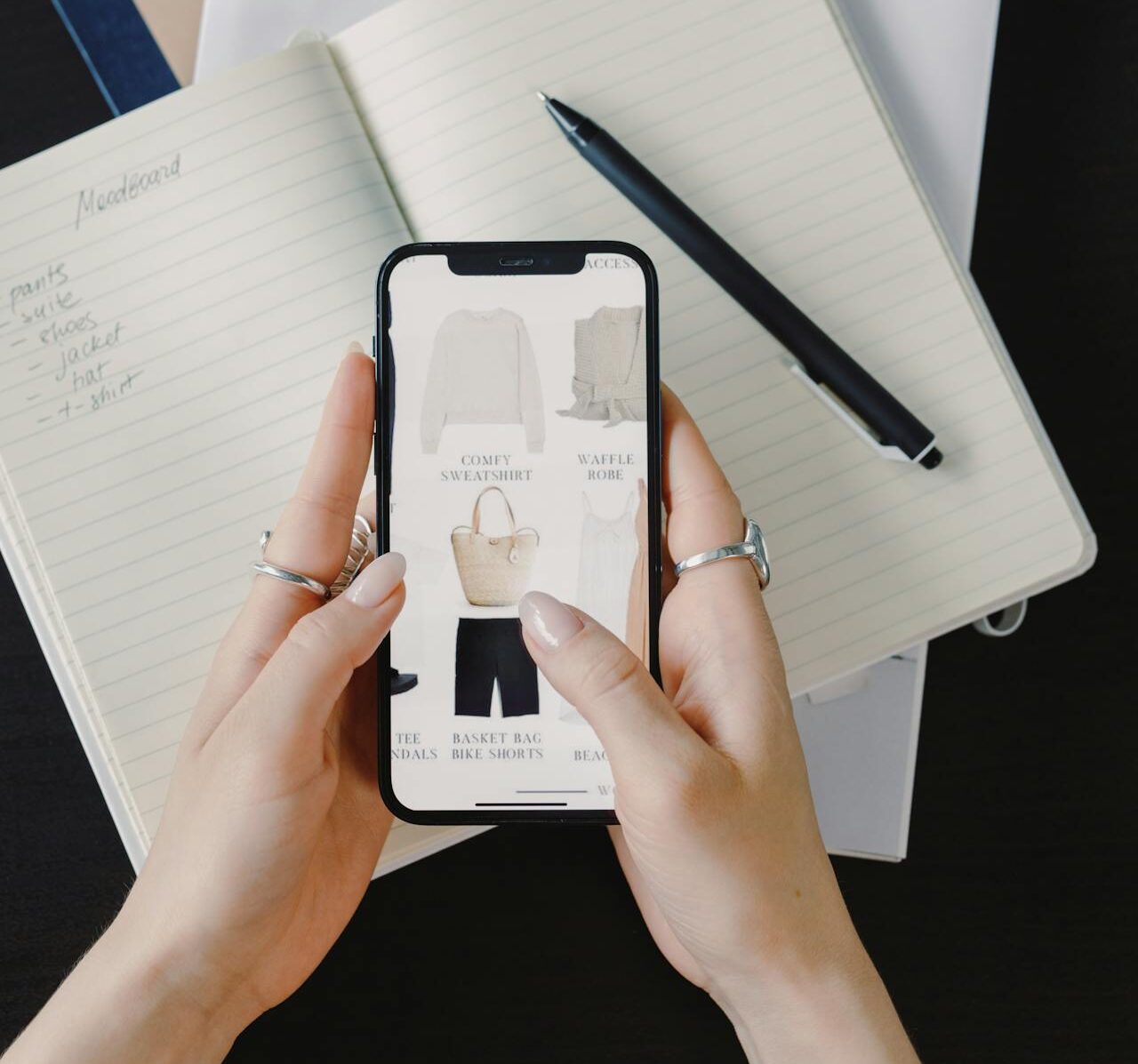 Mulher mexendo em uma loja virtual. Ao fundo, um caderno com itens a serem comprados. Essa figura representa o título da seção do artigo: Monte uma lista de compras inteligentes para a Black Friday
