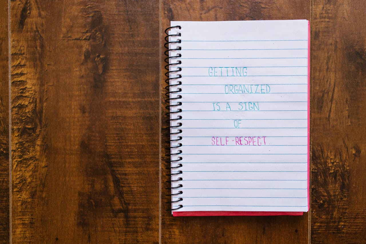 Caderno sobre uma mesa de madeira com o texto "Se organizar é um sinal de respeito próprio"